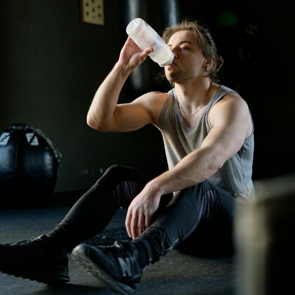 Healthy man drinking water after a successful strength session outdoors
